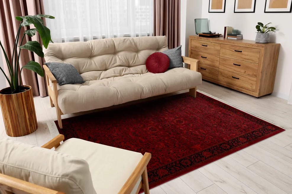 Ciemnoczerwony dywan orientalny pod jasną sofą w salonie z drewnianą komodą, dostępny w ofercie Dywany Witek.