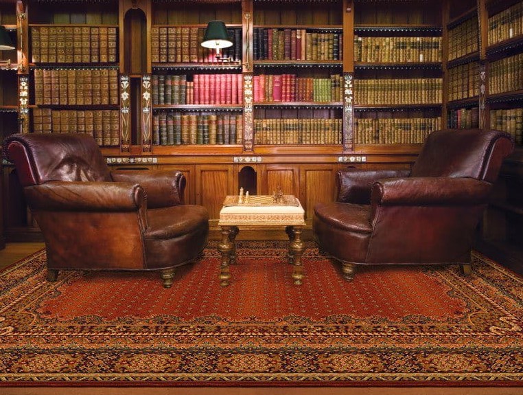 Bordowy dywan orientalny między skórzanymi fotelami w klasycznej bibliotece, dostępny w ofercie Dywany Witek.